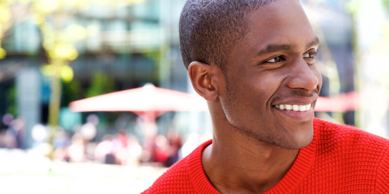 A young man smiling proudly with stain-free teeth.