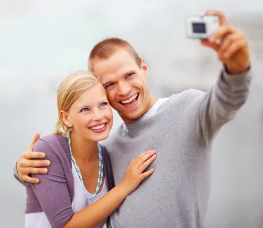 A smiling young couple taking a photo after teeth whitening treatements in Casper.